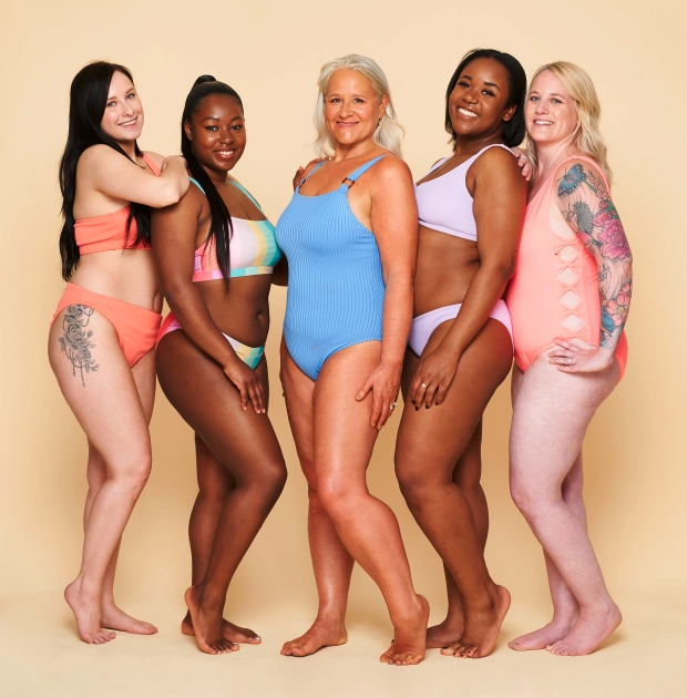 Five women, of varying ages, weights, heights, and ethnicities standing together, wearing swimsuits, to represent the differences in body type